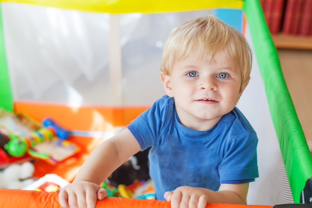 Cute little baby boy playing in colorful playpen