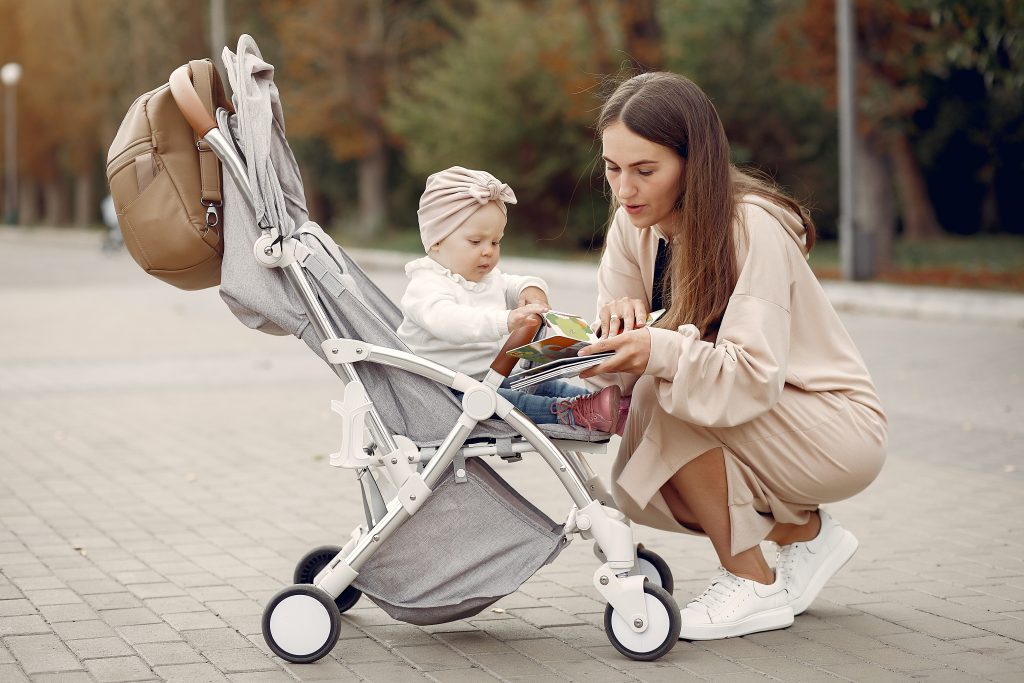 Young mother walking in a autumn park with carriage